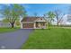 Charming home featuring an attached garage, a well-manicured lawn and a paved driveway on a sunny day at 4525 Shelbyville Rd, Indianapolis, IN 46237