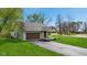 Charming single-story home with a brown garage door, light siding, green lawn and a paved driveway at 4525 Shelbyville Rd, Indianapolis, IN 46237