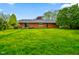 Wide backyard view featuring a brick house with a well-maintained lawn and mature trees creating a private outdoor space at 507 S Grant St, Brownsburg, IN 46112