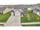 Aerial view of the home showcasing its well-maintained lawn, two-car garage, and nearby lake at 546 Freedom Dr, Pittsboro, IN 46167
