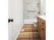 Bright bathroom featuring a modern tiled shower-tub, wood-look floors, and a wooden vanity at 6026 Oakbrook Ln, Indianapolis, IN 46254