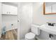 This powder room features a toilet and pedestal sink with a wall mirror and wood-look floors at 6026 Oakbrook Ln, Indianapolis, IN 46254