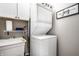 Compact laundry room features a stacked washer and dryer, a utility sink, and storage cabinets at 624 E Walnut St # 46, Indianapolis, IN 46204