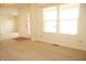 A bright living room features neutral carpeting, large windows, and a white front door with decorative glass at 6725 Tramcus Dr, Indianapolis, IN 46260