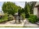 Cozy backyard patio area with a stone surface, dining table with four chairs, and lush landscaping at 1044 E Garfield Dr, Indianapolis, IN 46203