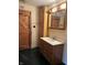 Bathroom with vanity, mirror, toilet, and unique wood door, showing potential for renovation at 10770 W 650 S, Columbus, IN 47201