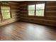 Bedroom with hardwood floors, wood-paneled walls, and large windows overlooking the landscape at 10770 W 650 S, Columbus, IN 47201