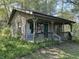 View of a modest cabin featuring a covered porch and set amidst abundant foliage at 10770 W 650 S, Columbus, IN 47201