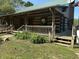 Quaint log cabin with a green roof, welcoming front porch, and beautiful landscaping at 10770 W 650 S, Columbus, IN 47201