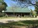 Charming log cabin featuring a green metal roof, covered front porch, and gravel driveway at 10770 W 650 S, Columbus, IN 47201