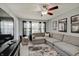 Comfortable living room featuring a large gray sectional, decorative curtains, and a ceiling fan at 11124 Winterwood Dr, Indianapolis, IN 46235