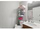 Bright bathroom with a white toilet, wooden vanity, sink, and chrome storage shelving at 11341 Abercairn Ct, Zionsville, IN 46077