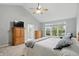 Main bedroom with ceiling fan, window view, and en suite bathroom is painted in pale gray at 11341 Abercairn Ct, Zionsville, IN 46077
