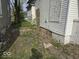 Side view of the house with boarded up windows and overgrown yard at 124 N Grant Ave, Indianapolis, IN 46201