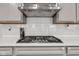 Close-up of a modern stove top with stainless steel range hood and subway tile backsplash in a well-lit, modern kitchen at 15120 Downham Dr, Fishers, IN 46037