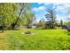 Spacious backyard featuring a fire pit, green grass, mature trees, and a shed at 251 Yorktown Rd, Greenwood, IN 46142
