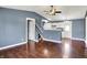 Open-concept living room with hardwood floors and a ceiling fan, flowing into the kitchen and stairway at 251 Yorktown Rd, Greenwood, IN 46142