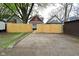 Fenced backyard with parking area; featuring a gate, mature tree, and access to alley at 344 N Addison St, Indianapolis, IN 46222