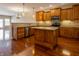 Open kitchen featuring wood cabinets, granite countertops, an island, and hardwood floors at 4061 Melbourne Dr, Columbus, IN 47203