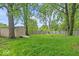 A lush backyard with mature trees, a fire pit, and a shed at 5719 Laurel Hall Dr, Indianapolis, IN 46226