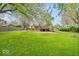 Expansive backyard with lush lawn, mature trees, patio, and fire pit perfect for outdoor entertaining at 6340 Monitor Ln, Indianapolis, IN 46220