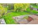 Aerial view of a spacious backyard with mature trees, a basketball court, a fire pit, and a long driveway at 6340 Monitor Ln, Indianapolis, IN 46220
