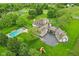 Aerial shot of a luxurious home with a pool, patio, and circular driveway surrounded by trees at 6990 Old Hunt Club Rd, Zionsville, IN 46077