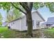 Side view of a house with light gray siding, black shutters and a covered porch, partially obscured by a large tree at 709 S Meridian St, Lebanon, IN 46052
