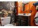 Stylish half-bathroom with dramatic wallpaper, dark vanity, decorative mirror, and orange accent walls at 71 S 9Th Ave, Beech Grove, IN 46107