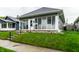 A quaint one-story home featuring a glass-enclosed front porch with steps to the landscaped front yard at 71 S 9Th Ave, Beech Grove, IN 46107
