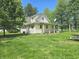 Charming yellow two-story home with a covered porch, surrounded by lush greenery and mature trees at 7561 N Hall School Rd, Monrovia, IN 46157