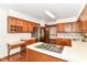 Well-lit kitchen with wooden cabinets, a built-in cooktop, and view to stainless steel refrigerator at 8242 Windhaven Cir, Indianapolis, IN 46236