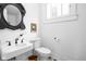Small bathroom with vintage-style mirror, pedestal sink, toilet, and patterned tile flooring at 946 Stillwell St, Indianapolis, IN 46202