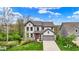 Charming home showcasing beautiful curb appeal, an orange front door, lush landscaping, and a well-maintained lawn at 10294 Pigato Dr, Zionsville, IN 46077