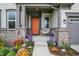 Inviting front porch with an orange door, featuring potted flowers and seating that adds a welcoming touch to the home at 10294 Pigato Dr, Zionsville, IN 46077