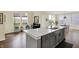 Open concept kitchen with grey cabinets, an island with seating, and an adjacent living area at 10294 Pigato Dr, Zionsville, IN 46077