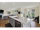 Open concept kitchen with grey cabinets, an island with seating, and an adjacent living area at 10294 Pigato Dr, Zionsville, IN 46077
