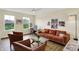 Cozy living room with a brick colored couch, hardwood floors, a ceiling fan and a decorative glass coffee table at 10294 Pigato Dr, Zionsville, IN 46077