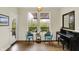 Bright living room with a piano, blue chairs, and a view to an outdoor terrace through large windows at 10294 Pigato Dr, Zionsville, IN 46077
