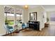 Bright living room with a piano, blue chairs, and a view to an outdoor terrace through large windows at 10294 Pigato Dr, Zionsville, IN 46077
