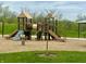 Community playground with slides, swings, and a climbing structure surrounded by lush greenery and wood chip ground cover at 10294 Pigato Dr, Zionsville, IN 46077