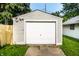 Image of detached garage with weathered wood siding, white door, and concrete driveway at 1030 N Butler Ave, Indianapolis, IN 46219