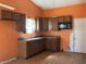 A well-lit kitchen featuring warm orange walls, dark cabinets, and laminate wood flooring at 10569 Folsom Dr, Indianapolis, IN 46235