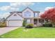 Charming two-story home featuring a well-manicured lawn, attached garage, and inviting front porch with decorative shutters at 11205 Echo Ridge Ln, Indianapolis, IN 46236