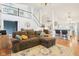 Open-concept living area with a plush sectional sofa, hardwood floors, and a staircase leading to the upper level at 11205 Echo Ridge Ln, Indianapolis, IN 46236