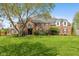 Beautiful brick home with a lush green lawn and mature tree providing shade at 11469 Burkwood Dr, Carmel, IN 46033