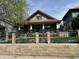 Charming craftsman-style home with green lawn, inviting porch, and brick and green metal fence at 1337 N Olney St, Indianapolis, IN 46201