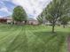 Well-manicured backyard featuring a spacious lawn, mature trees, and a wooden deck, perfect for outdoor entertaining at 1395 Heron Ridge Blvd, Greenwood, IN 46143