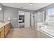 Bright bathroom featuring a soaking tub, shower, vanity with wood cabinets, and neutral tile flooring at 15936 Symphony Blvd, Noblesville, IN 46060