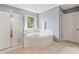 Bright bathroom with a large soaking tub, separate shower, and natural light from the window at 15936 Symphony Blvd, Noblesville, IN 46060